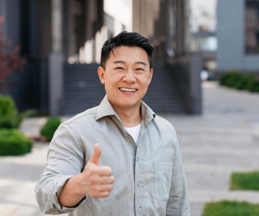 Portrait,Of,Positive,Asian,Man,Standing,Outdoors,And,Gesturing,Thumb